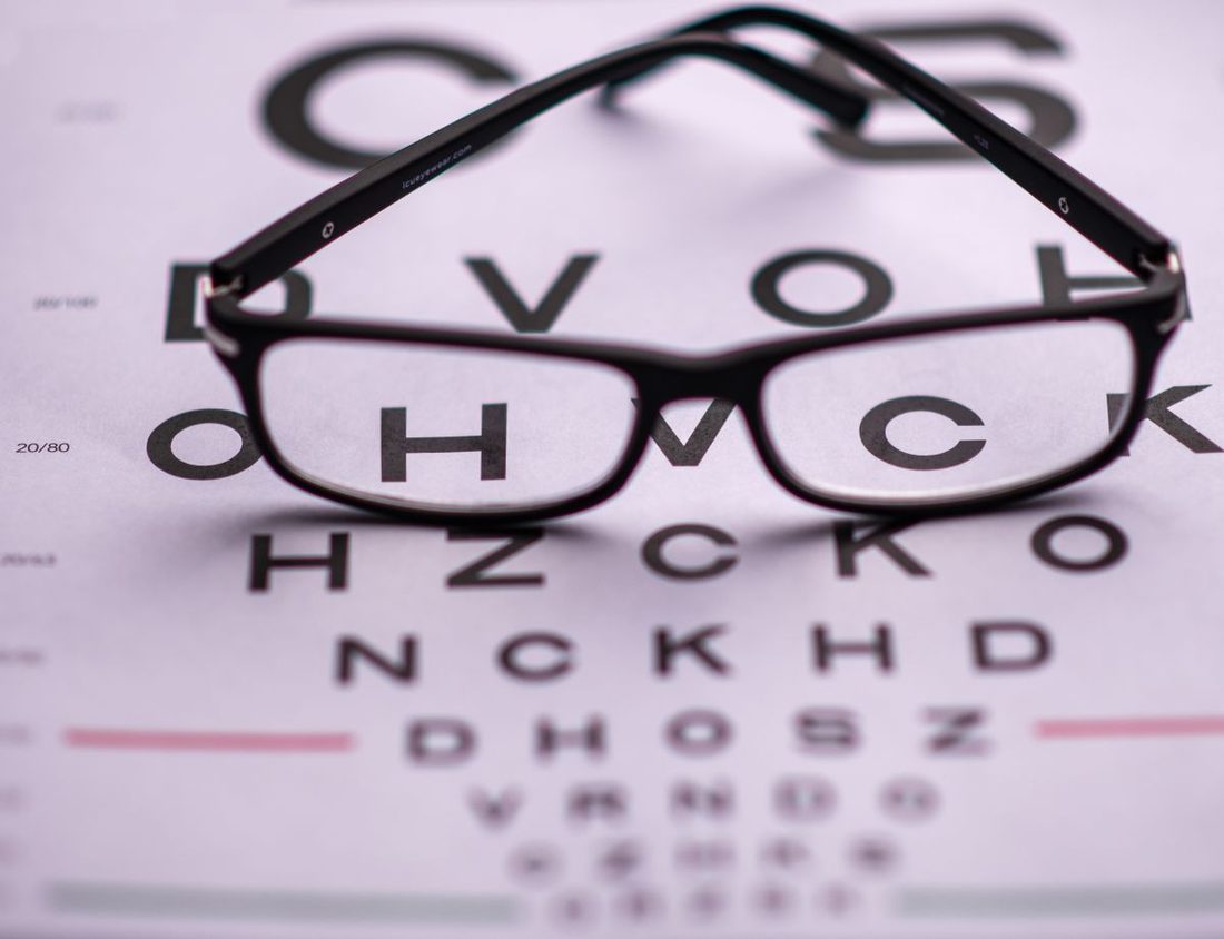 A pair of eyeglasses resting on an eye-test chart (illustrative stock photo)